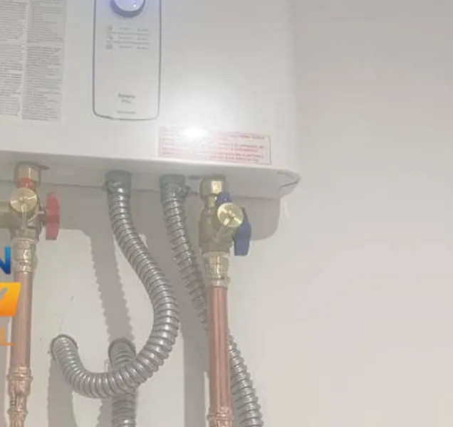 A wall-hung tankless water heater with new copper supply lines, isolation valves and a stainless gas connector